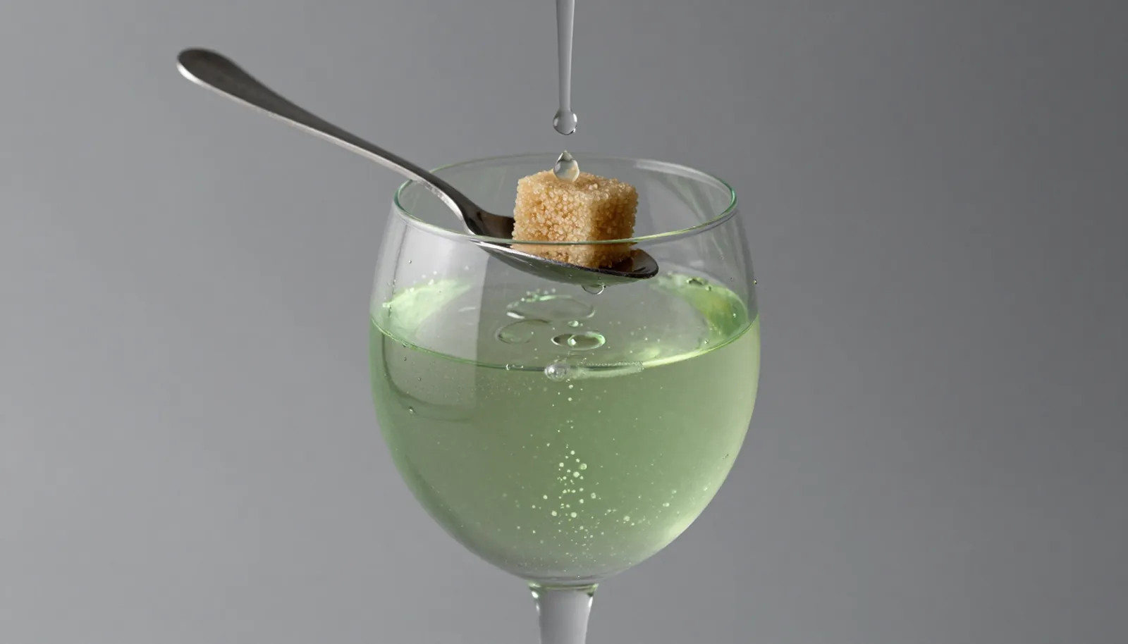 Ly absinthe xanh với thìa lỗ và viên đường phía trên