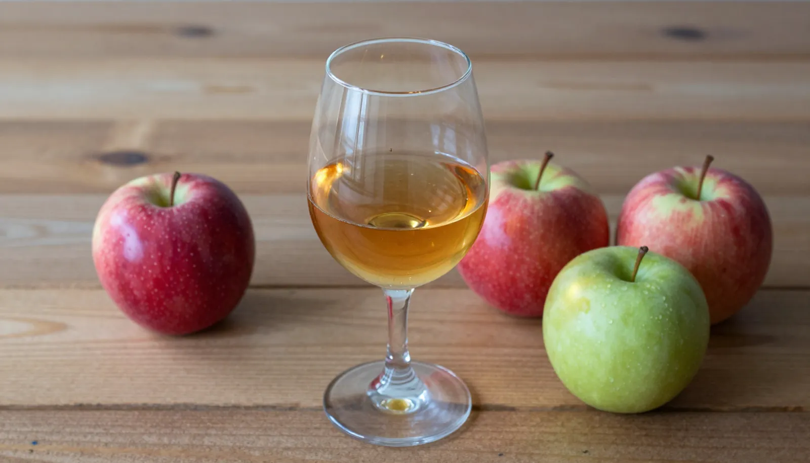 Ly calvados vàng óng bên những quả táo đỏ và xanh