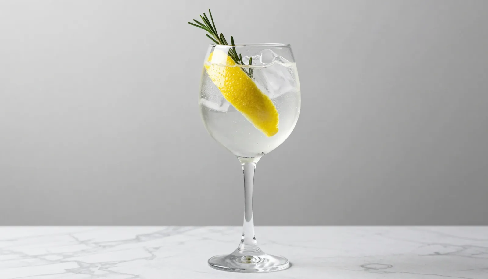Ly gin tonic với đá, vỏ chanh và nhánh hương thảo